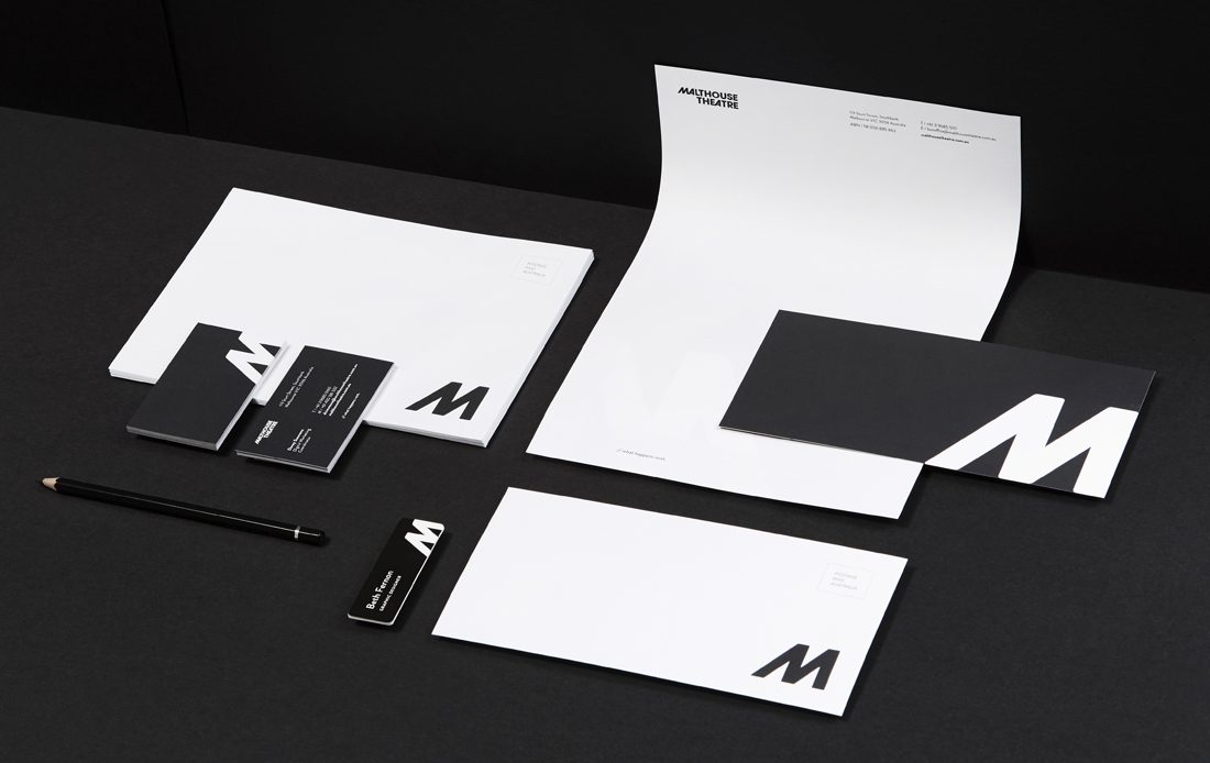 Brand stationary with two envelopes, business cards, pencil, nametag, letterhead, card and black paper background